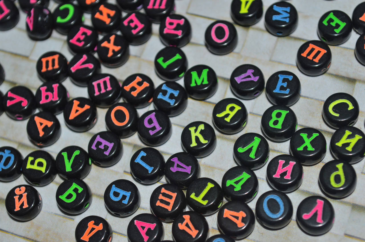 

Яркая бусина с буквой русского алфавита на черном фоне.круглая