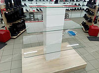Стелаж острівної або скляна гірка для магазину взуття. Стелаж має підставу під основний колір меблів у магазині і білого кольору колону на якій розміщені скляні полиці для демонстрації взуття. Скляні полиці цільні, всі кріплення приховані