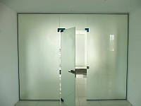 Стеклянная маятниковая дверь в офисе из белого матового каленного стекла