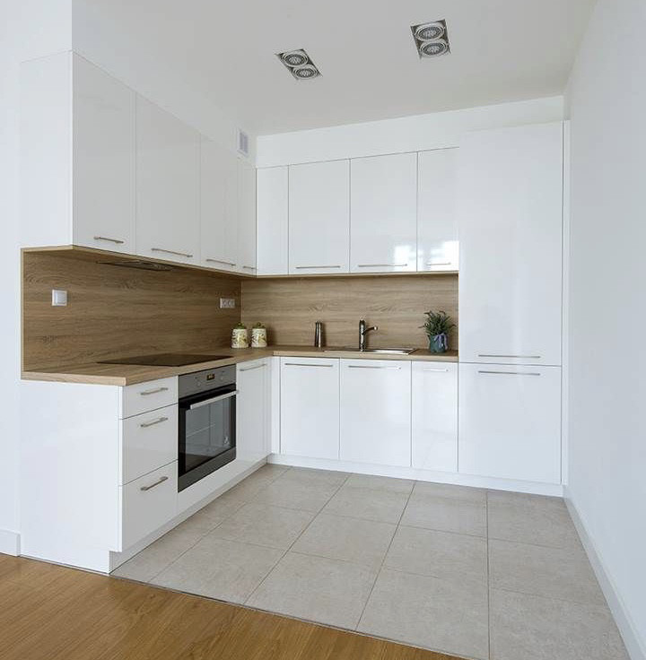 Біла глянсова кухня з ручками та робочою поверхнею під дерево