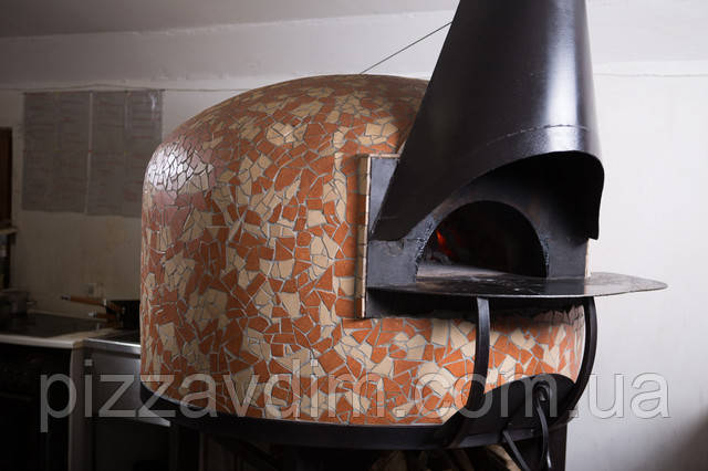 Піч на дровах для піци прикрашена мозаїкою знаходиться на кухні ресторану