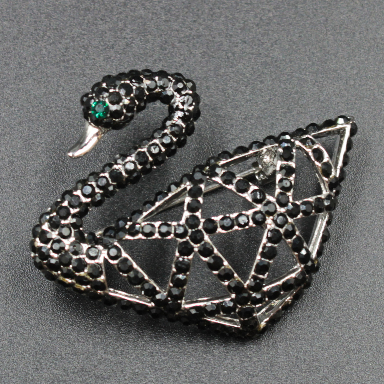 Брошка металева на сріблястій основі лебідь з чорними та смарагдовими стразами розмір виробу 45х30 мм