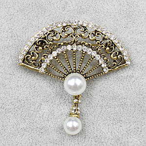 Брошка металева на золотистій основі віяло з білими стразами та намистиною висулькою розмір 50х50 мм