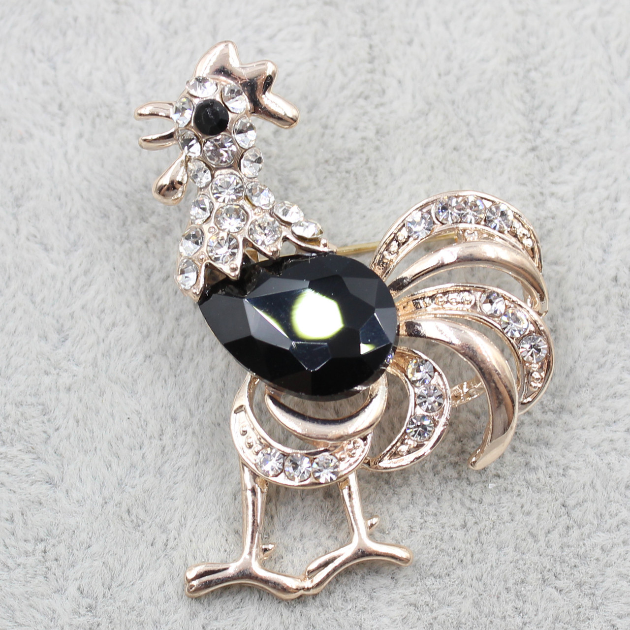 Брошка металева на золотистій основі півень у білих стразах із чорним агатом розмір виробу 50х38 мм