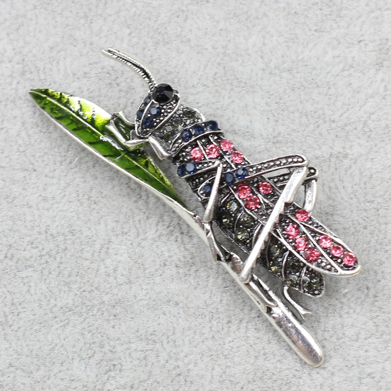 Брошь металлическая серебристая кузнечик на листике с синими и розовыми камушками размер изделия 70х20 мм