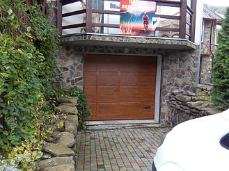 Гаражные секционные ворота Ryterna (Литва) со встроенной калиткой в цвете золотой дуб с гладким типом полотна SLICK. 