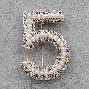 Брошка металева на золотистій основі з білими стразами та намистинами брендова розмір виробу 40х25 мм