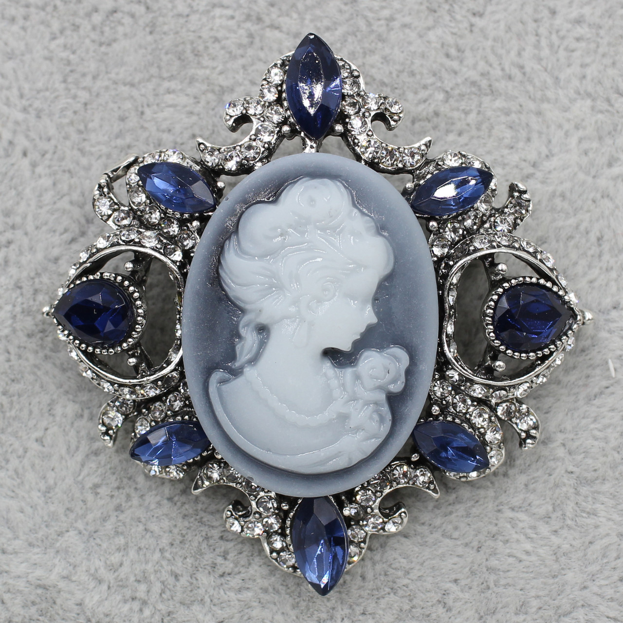 Брошка металева на сріблястій основі кам'яна в оправі декорована стразами та кристалами 50х55 мм