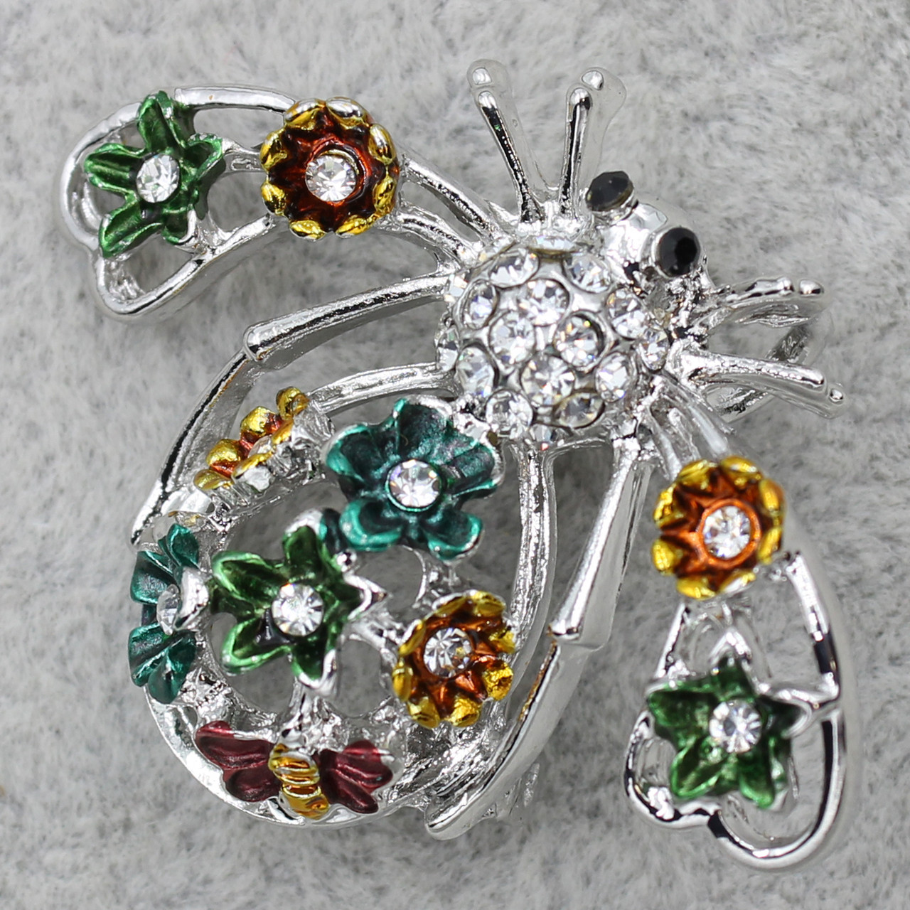 Брошка у формі метелика сріблястого кольору декорована різнобарвними квіточками в стразах розмір 30х40 мм