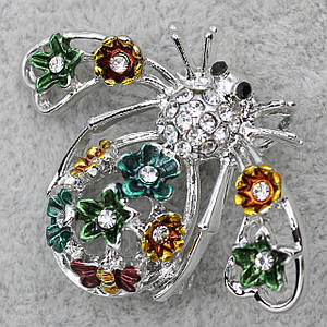 Брошка у формі метелика сріблястого кольору декорована різнобарвними квіточками в стразах розмір 30х40 мм