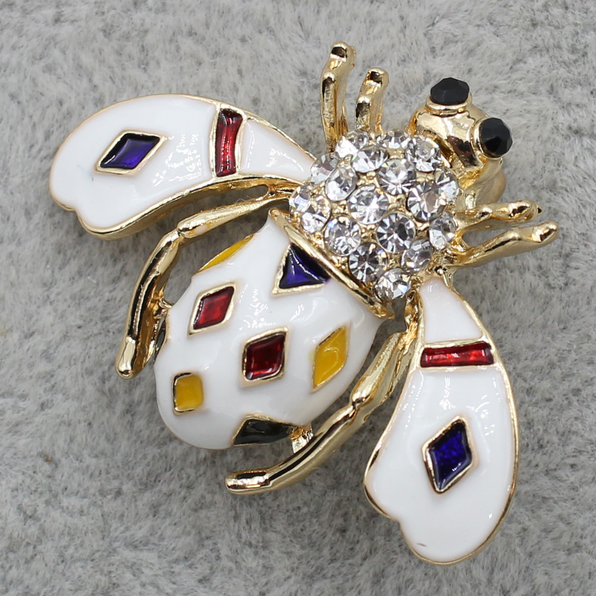 Брошка шміль із білою емаллю з різнобарвним камінням і стразами золотистого кольору розмір виробу 35х30 мм