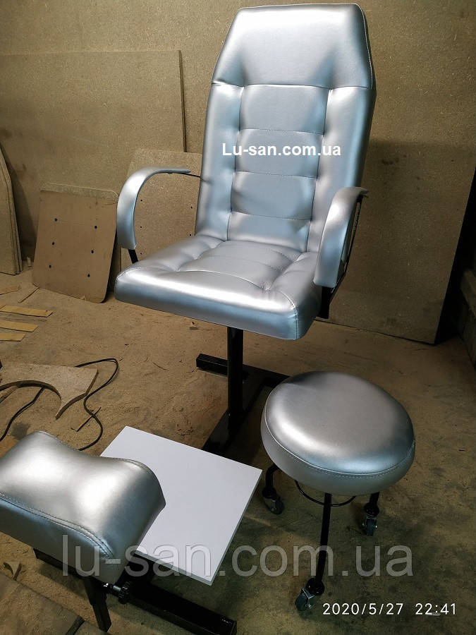 Сріблясте педикюрне крісло для педикюру з підставкою для ніг та стільцем для майстра.