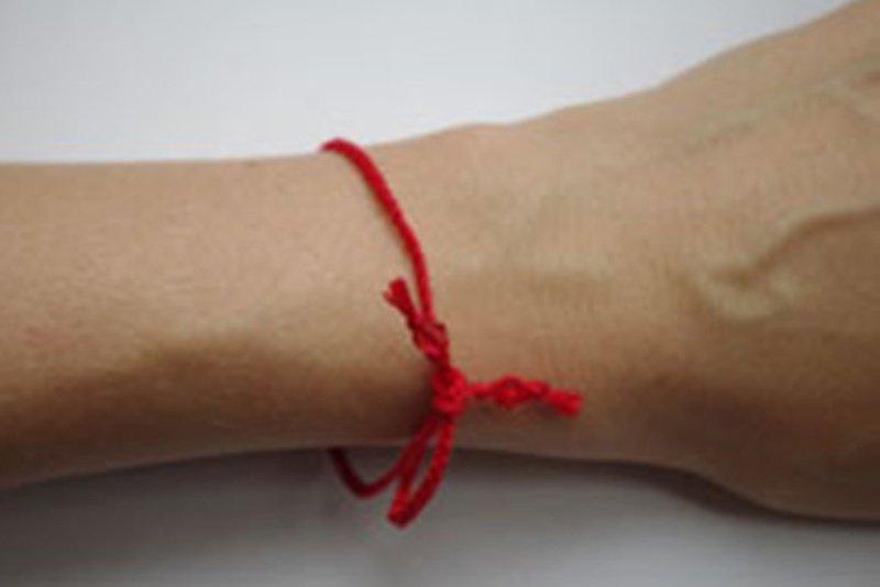 Завязанная нитка красная на руке