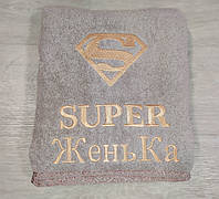 Бежевое именное подарочное банное полотенце 140*70см с вышивкой значка супермена и надписи "SUPER ЖеньКа"