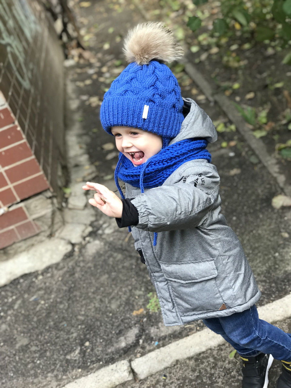 В'язана утеплена дитяча шапочка на зав'язках із натуральним хутряним бубоном для хлопчика ручної роботи.