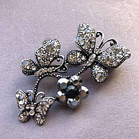 Яскрава Брошка метал під крапельне срібло метелики, що сидять на квітці гірлянда, темні і білі стрази 55х34мм + - купити біжутерію