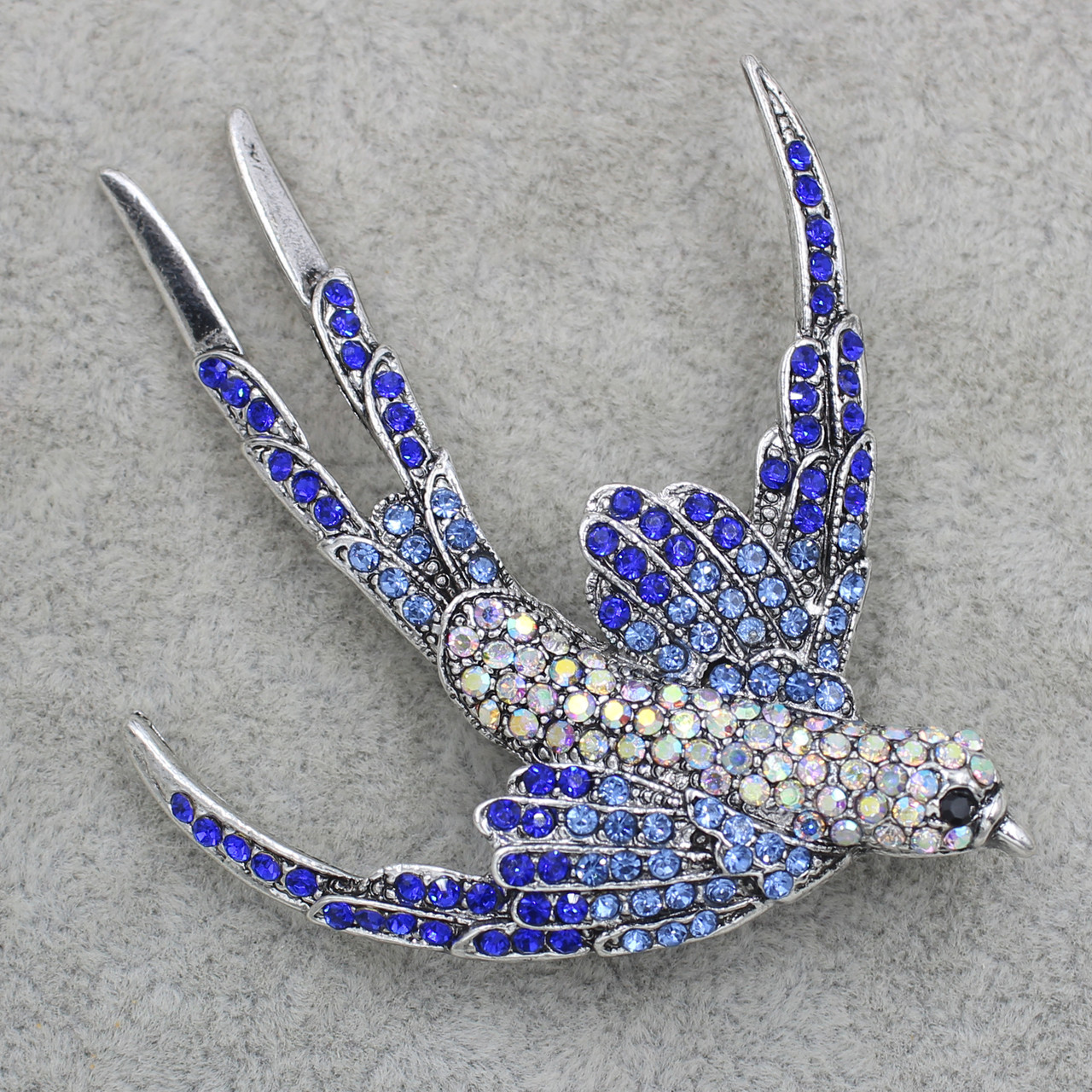 Брошка металева срібляста ластівка з кристалами, що переливаються, розмір виробу 60х55 мм