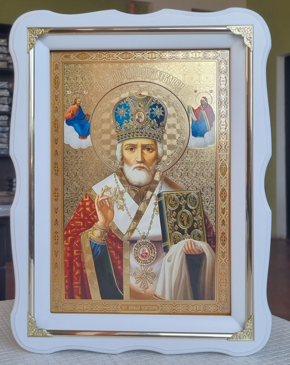 Ікона Святий Миколай чудотворець у білому дерев'яному фігурному кіоті під склом з декор.куточками, кіот 37×27, сюжет 20×30.
