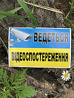 Табличка-наклейка жовто-блакитна з написом "Ведеться відеоспошкодження" українською мовою