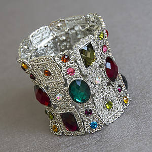 Браслет жіночий масивний сріблястого кольору м'який на гумці з різнобарвними кристалами ширина 60 мм