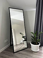 Підлогове дзеркало в тонкій чорній рамі на ніжці