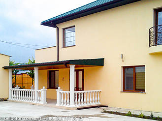 Неожиданно гармонично сочетается белая балюстрада и колонны с  деревянным потолком веранды