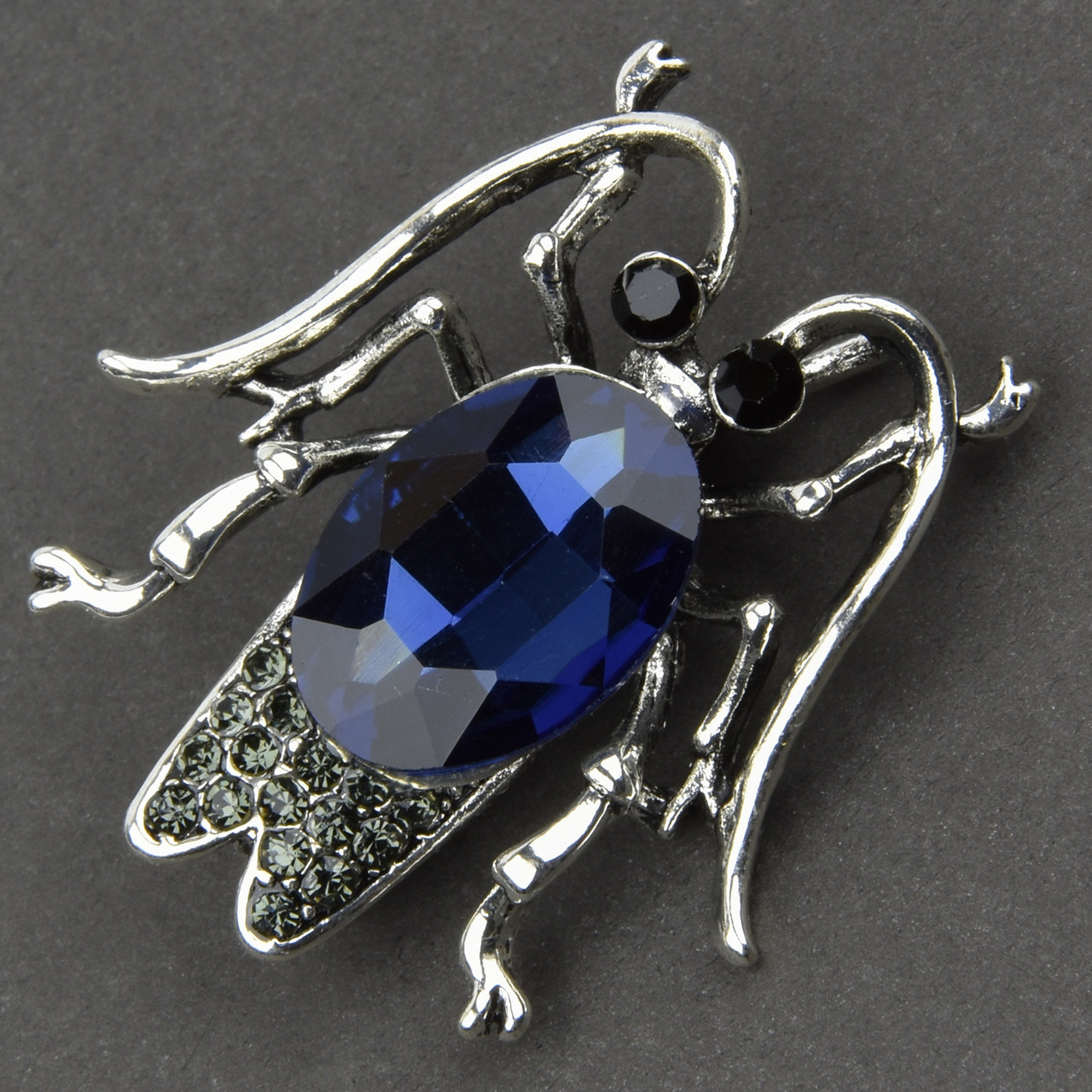 Брошка металева на сріблястій основі комаха із синім кристалом і сірими стразами розмір 40х35 мм