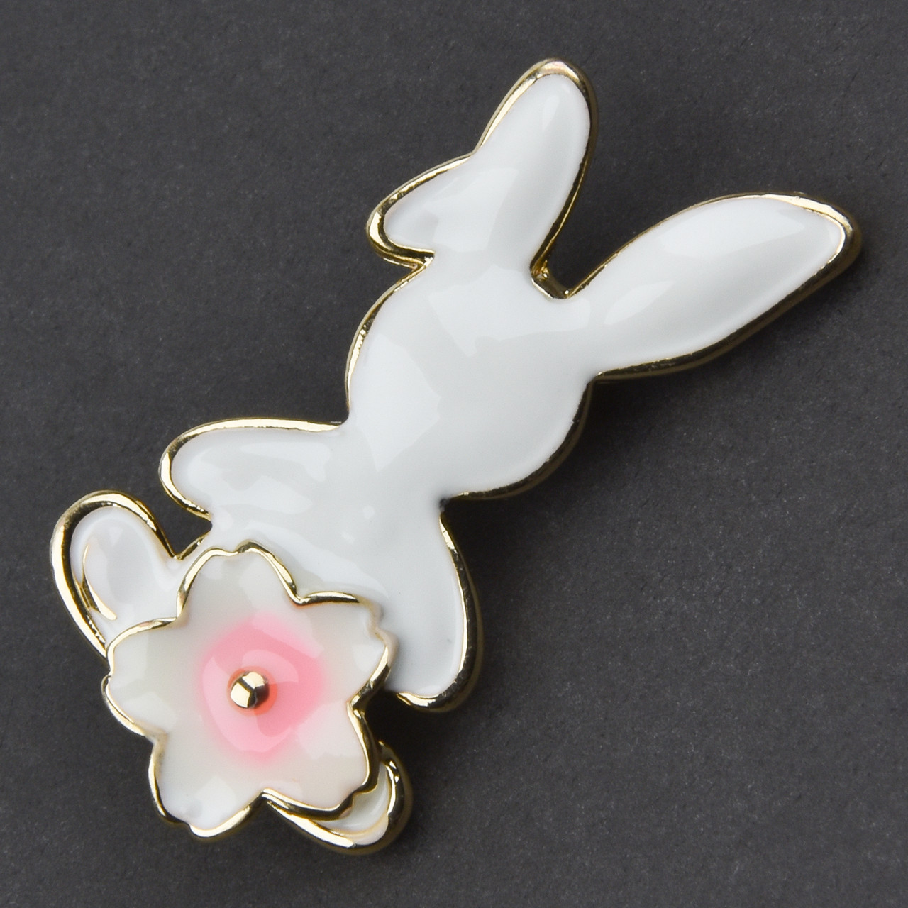 Брошка металева на золотистій основі зайчик із квіточкою покрита білою емаллю розмір 40х20 мм