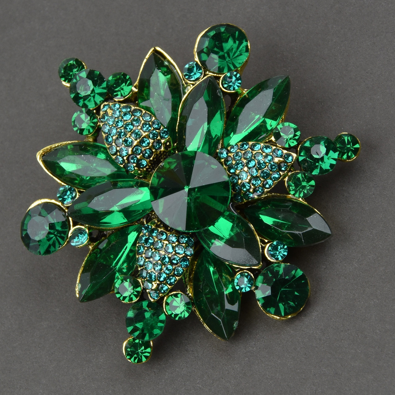 Брошка металева на золотистій основі квіточок зі смарагдовими масивними кристалами розмір 50Х55 мм