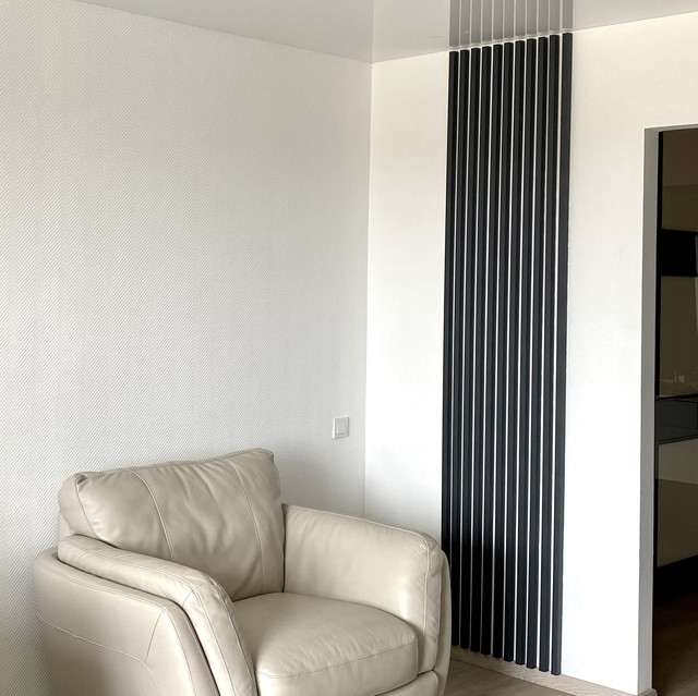 Рейки на стіні колір антрацит у вітальні біля білого крісла