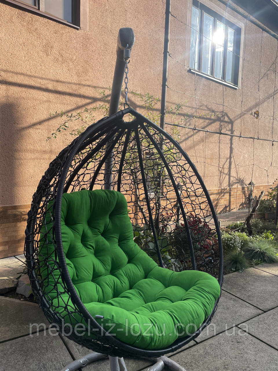 Крісло-кокон коричневого кольору із зеленою подушкою