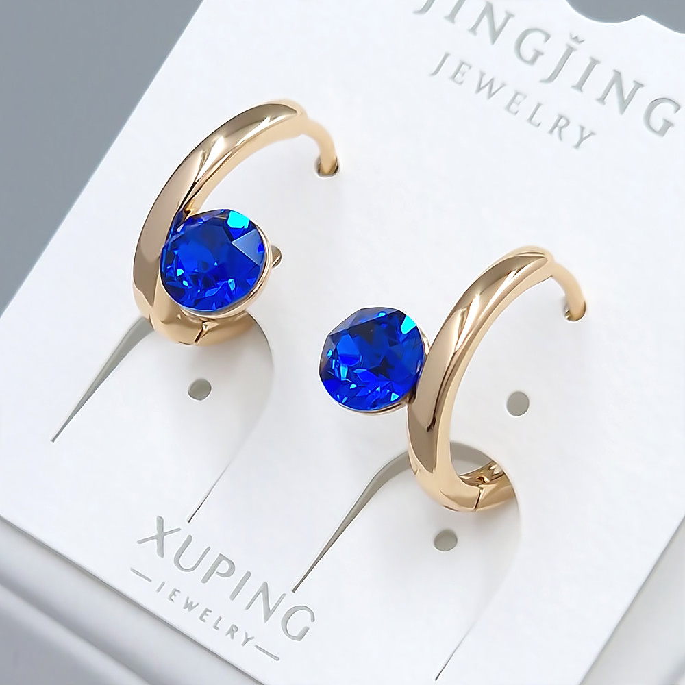 Сережки XР. Позолота 18К. Камені: Swarovski синього кольору. Діаметр: 15 мм. Ширина: 8 мм.