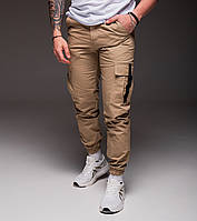 Бежевые брюки джоггеры из хлопка на манжетах с накладными карманами и карабинами M