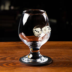 Коньячний келих із гральним кубиком. Гральний кубик в келиху для коньяка.