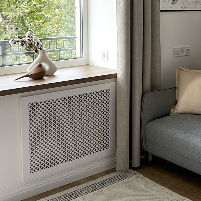 Біла решітка на батаре опалення, що розташована під вікном у вітальні