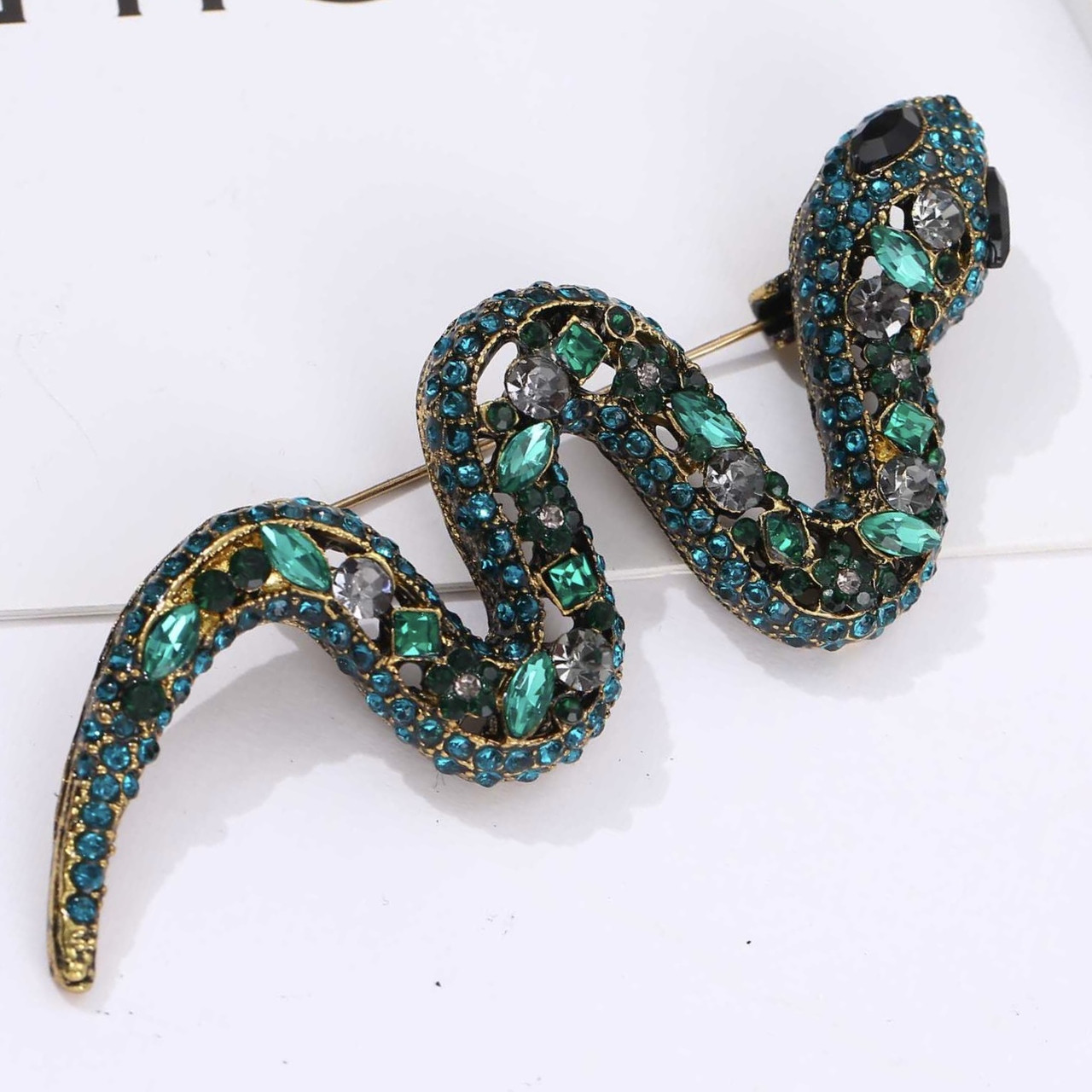 Брошка металева на золотистій основі змія зі смарагдовими кристалами розмір виробу 70х25 мм