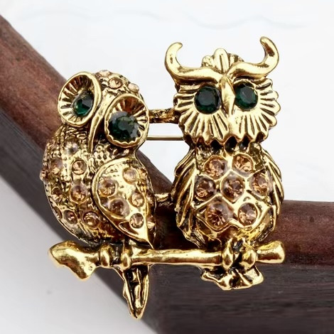Брошка металева на золотистій основі дві сови на гілочці з бежевими та зеленими стразами розмір 30х35 мм