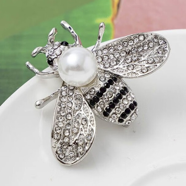 Брошка металева на сріблястій основі бджола з білими та чорними стразами та намистиною розмір 35х40 мм