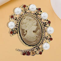 Брошка металева на золотистій основі камея з білими намистинами та стразами розмір виробу 40х35 мм