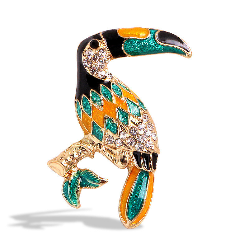 Брошка металева золотиста Тукан на гілочці в стразах покрита кольоровою емаллю розмір виробу 40х30 мм