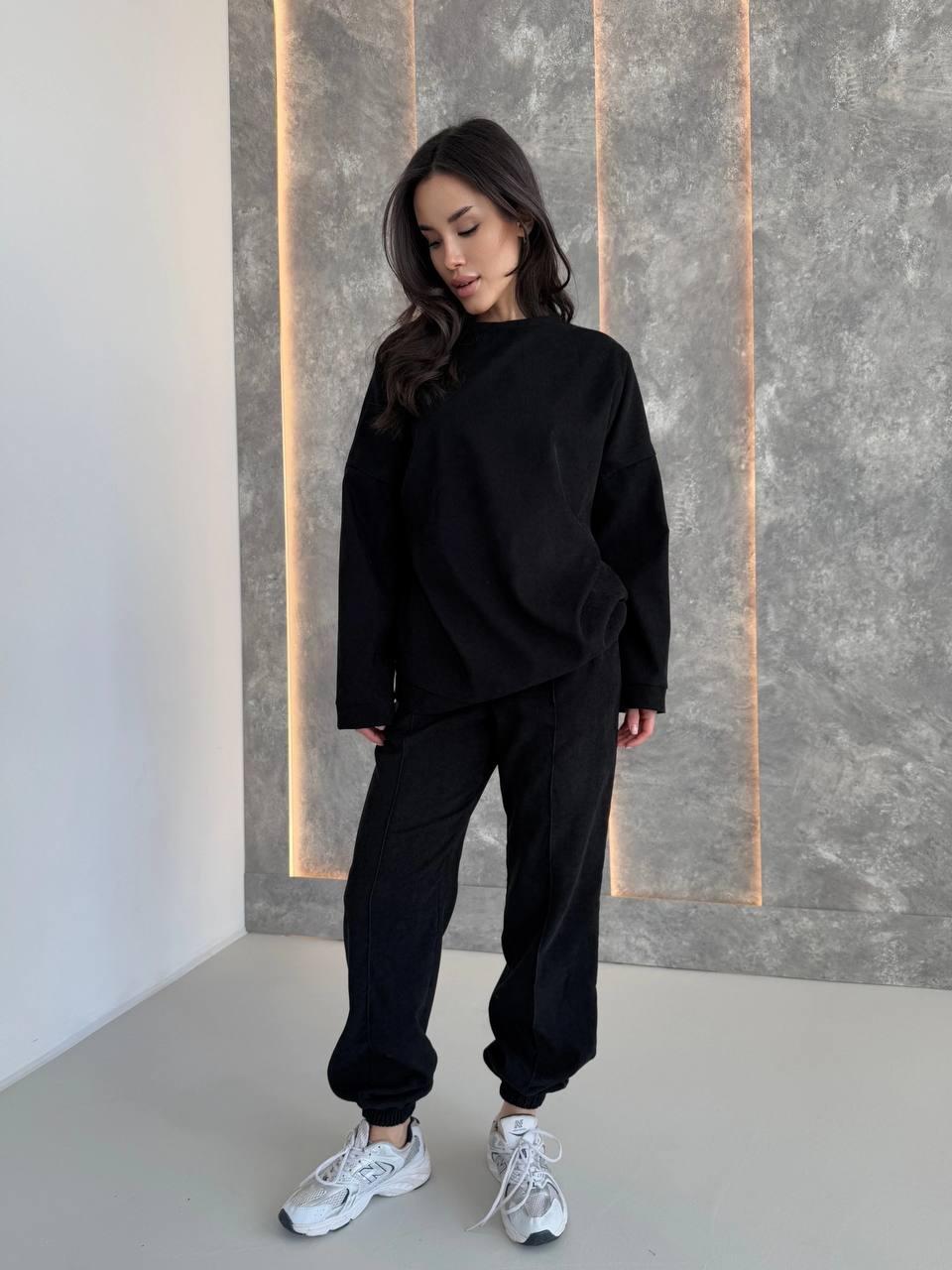 Жіночий чорний об'ємний костюм-двійка з приємного вельвету: кофта прямого крою і штани з манжетами, фото 1