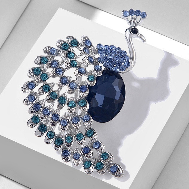 Брошка металева на сріблястій основі павич із різнобарвними камінцями розмір 65х40 мм