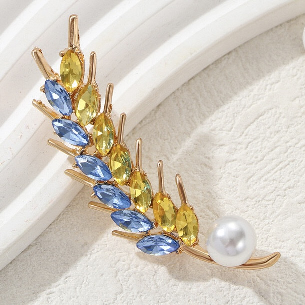 Брошка на золотистій основі колосок із блакитними та жовтими стразами та білою намистиною розмір виробу 65х20 мм