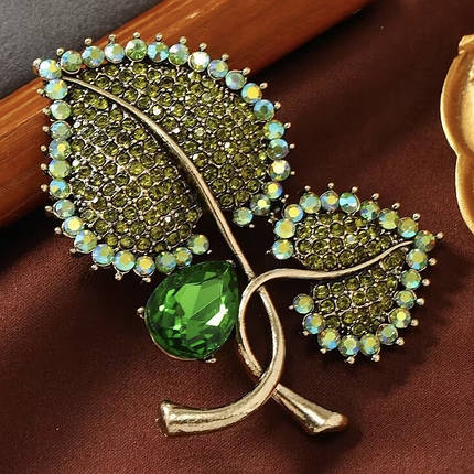 Брошка на золотистій основі листочки із зеленими кристалами, що переливаються, розмір виробу 70х55 мм, фото 1