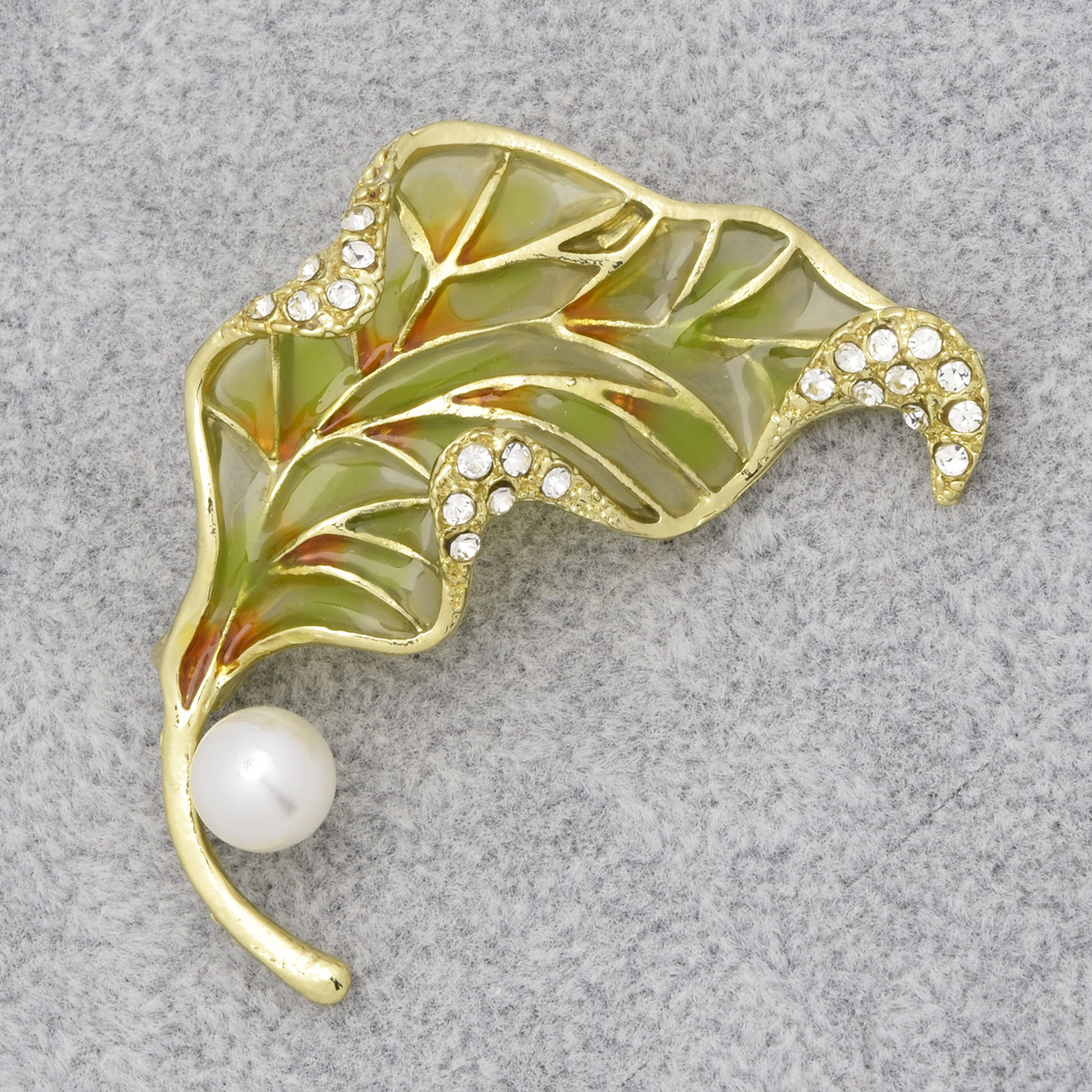Брошка на золотистій основі листочок зі стразами та білою намистиною покрита кольоровою емаллю розмір виробу 50х35 мм