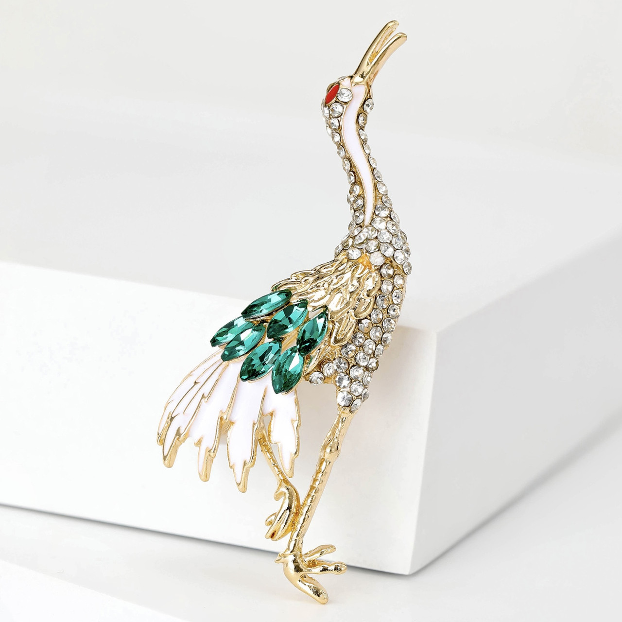 Брошка металева золотиста журавель покрита білою емаллю зі смарагдовими стразами розмір виробу 70х25 мм