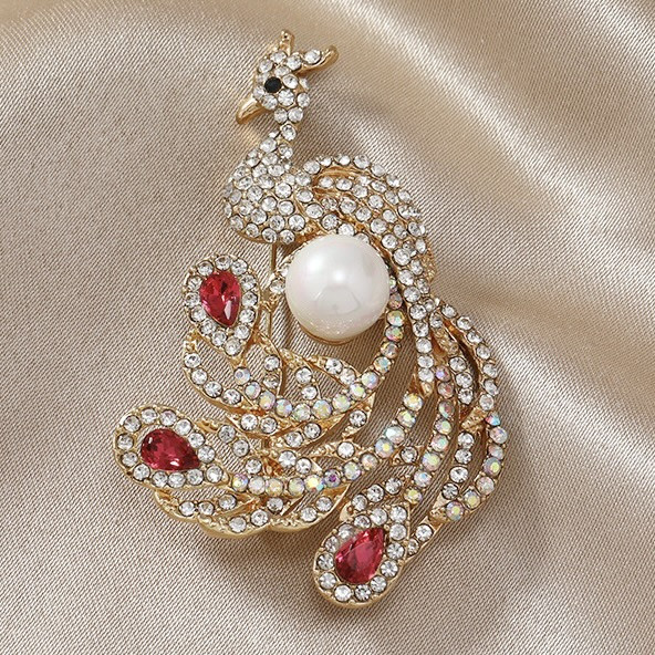 Брошка металева на золотистій основі птиця з білою намистиною й білими та рожевими стразами розмір 60х35 мм