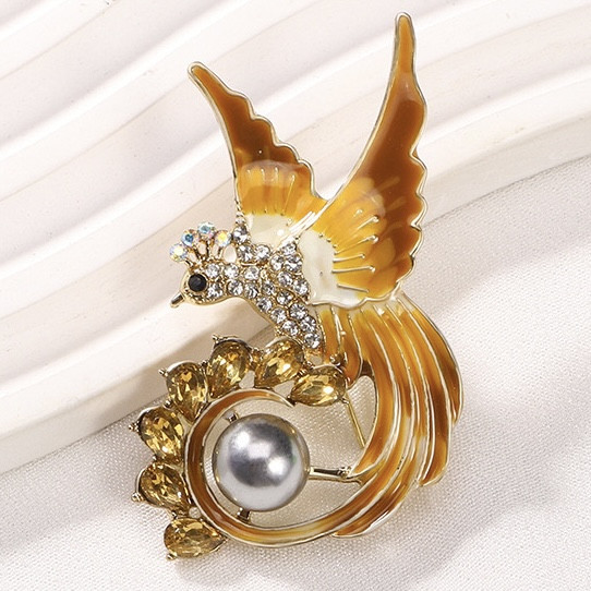 Брошка металева на золотистій основі птиця з жовтими стразами покрита емаллю розмір виробу 50х35 мм