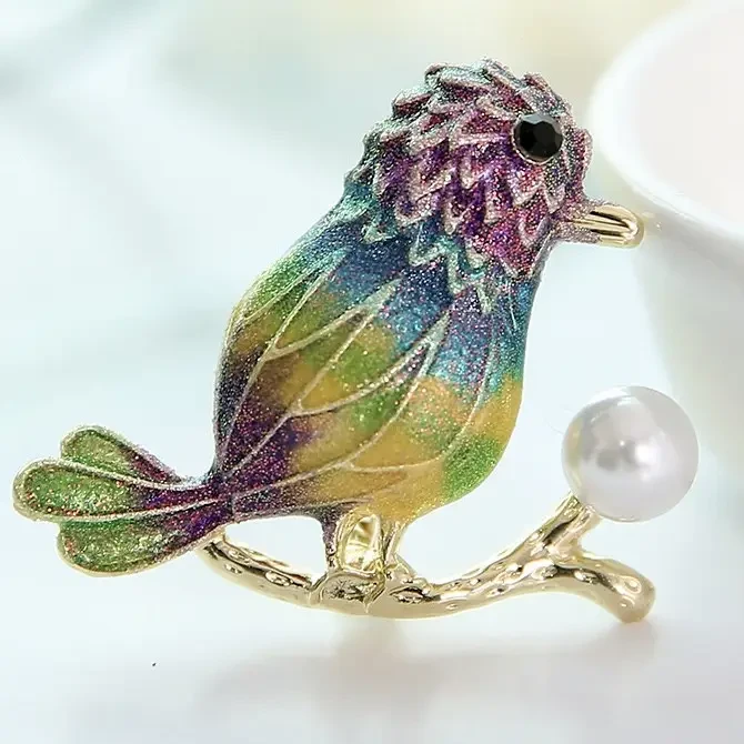 Брошка металева на золотистій основі пташка в блискіточках із намистиною покрита кольоровою емаллю розмір 35х40 мм