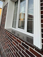 Віконний відлив з токівського граніту на фоні коричневої цегли